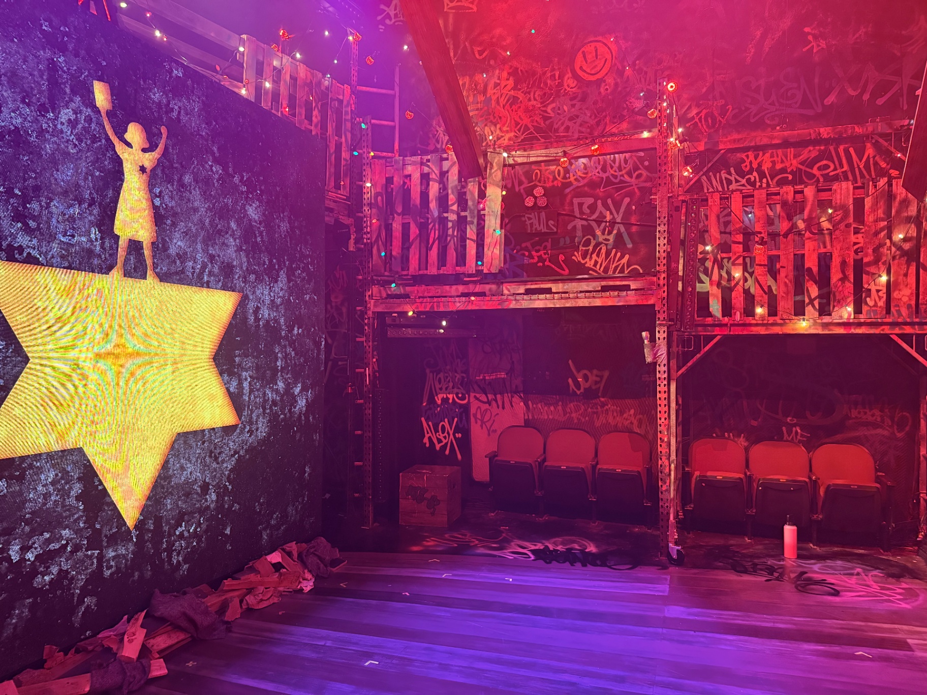 Full stage view of the SLAM FRANK set with glowing iconography, graffiti scaffolding, and atmospheric lighting