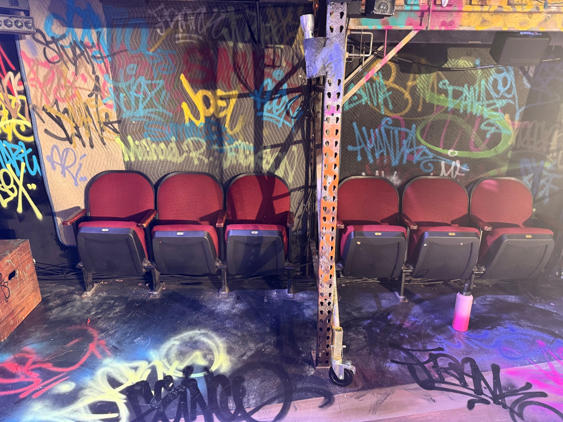 Rows of red on-stage seats set against a graffiti-covered backdrop at SLAM FRANK